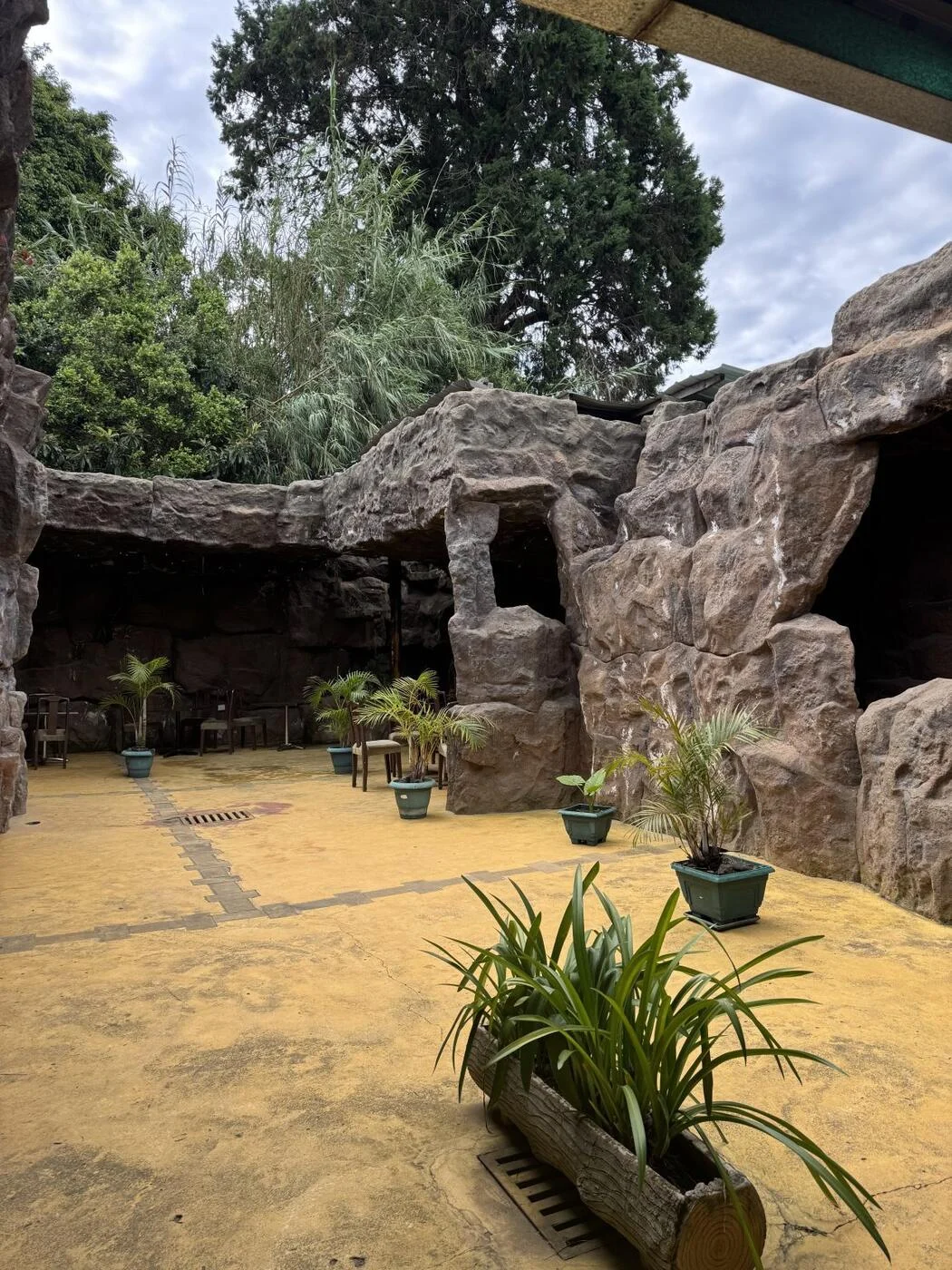 Yellow-tinted concrete patio framed by stone walls and potted plants