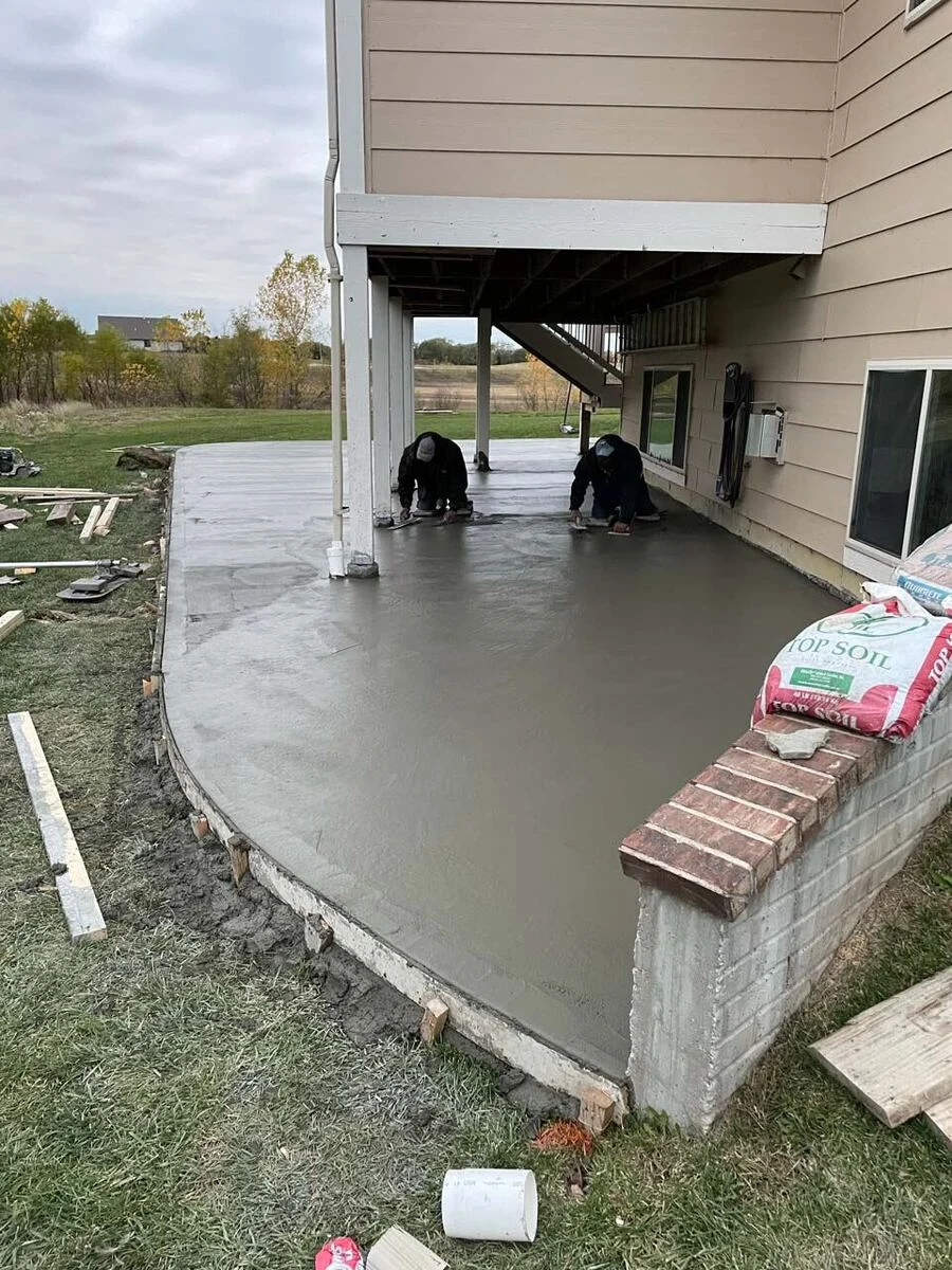 Finishers placing and leveling a new backyard concrete patio slab